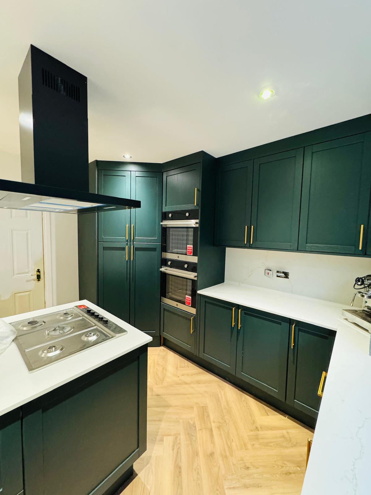 Green shaker kitchen detail with gas hob and marble worktop